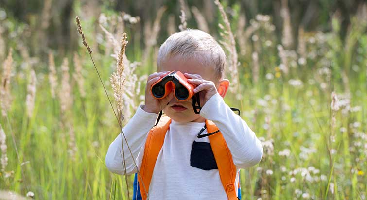 Junge schaut durch Fernglas in der Natur